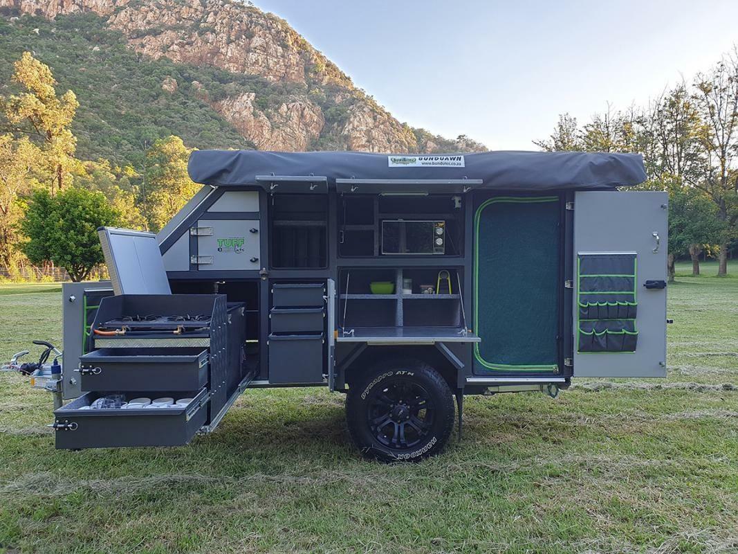 Shumba 2 offroad caravan with kitchen open, parked on grass below a mountain
